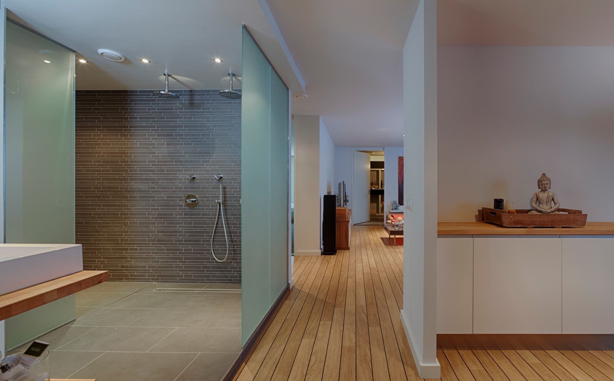 Afgebouwde kelder met inloopdouche achter glas en een houten vloer
